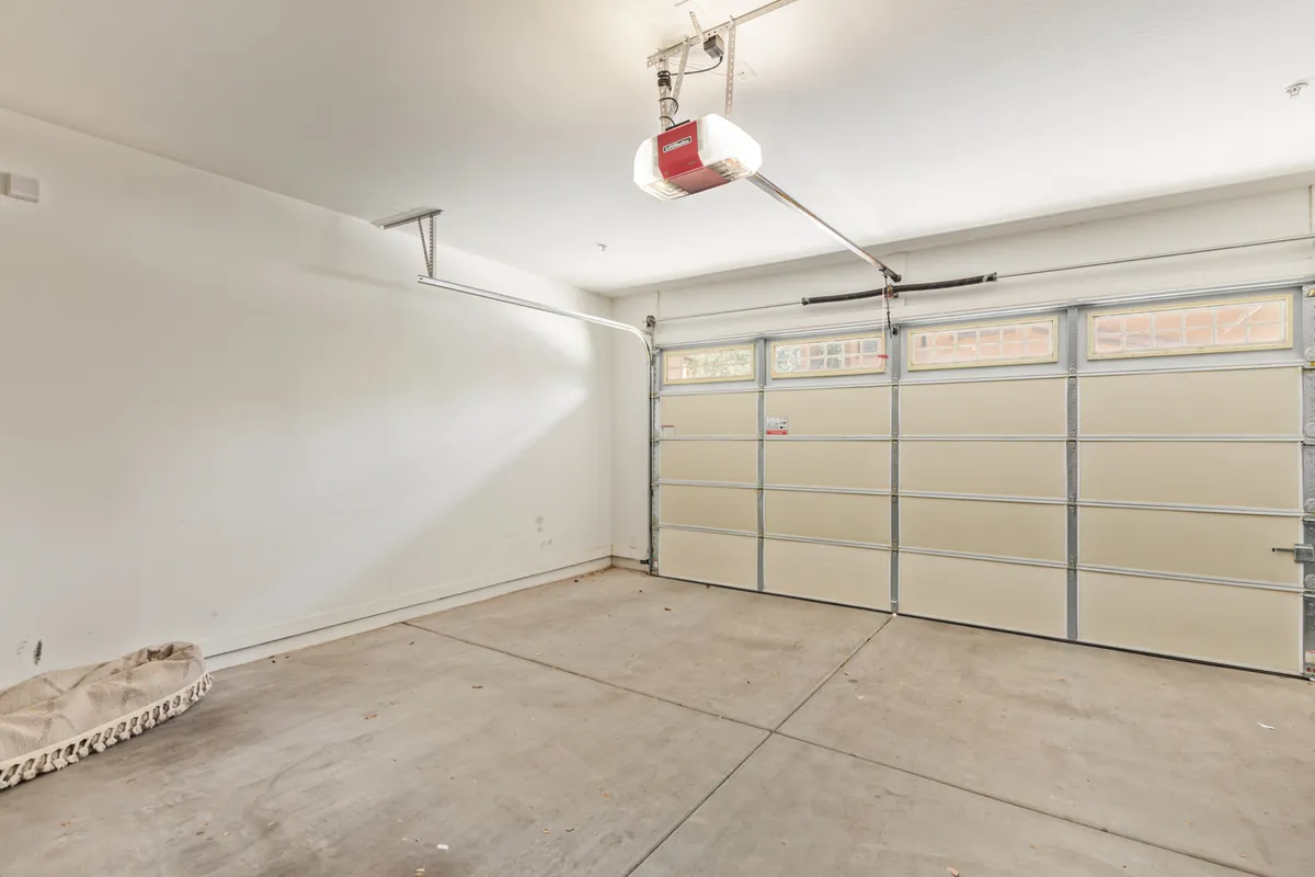 A spacious two-car garage with a clean concrete floor, open garage door, and ample wall space for storage or projects. The image highlights both parking and organizational possibilities.